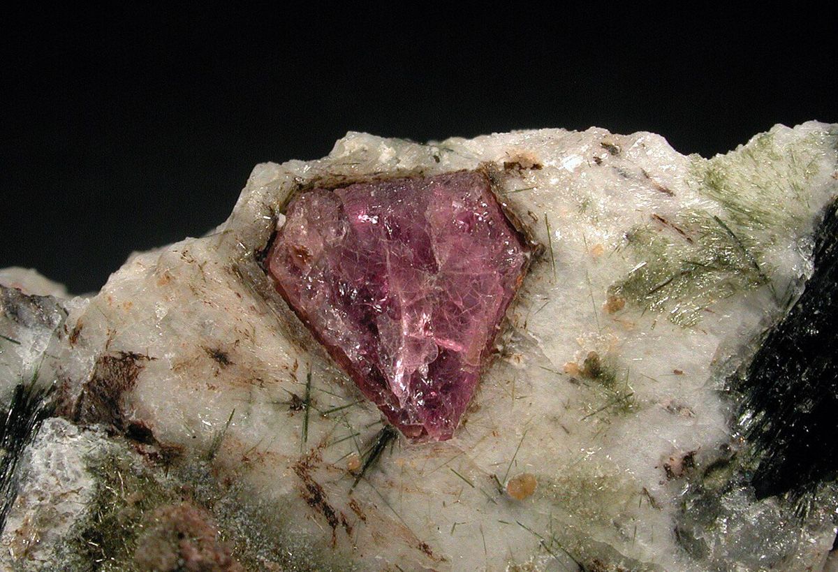 Cristal d'eudialyte rose violacé sur une roche claire