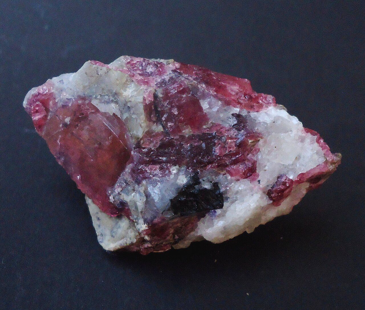 Morceau d'eudialyte rouge framboise dans une roche blanche